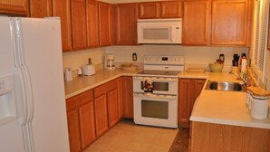 Una cocina con armarios de madera, un refrigerador blanco, un microondas, una estufa y un lavabo.