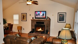 Una sala de estar con chimenea, sofás de cuero, un televisor y una lámpara.
