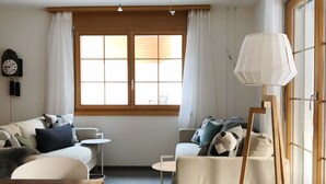 A living room with a wooden table, two sofas, a small round table, and a lamp.
