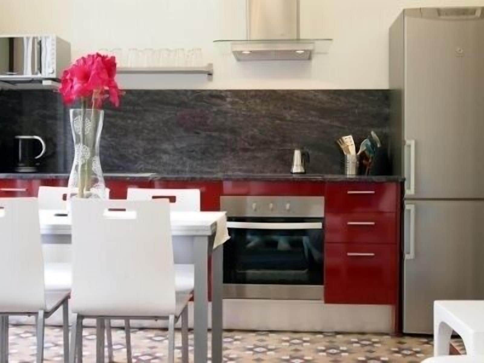 Een moderne keuken met witte stoelen, een rode kast en een roestvrijstalen oven.
