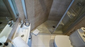 A modern bathroom with a glass shower enclosure, a white sink, and a toilet. - 3BR/3BA Painted in White Apartment with Balcony. Free luggage storage service. (Barcelona)