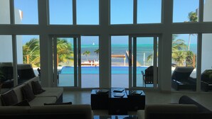 A spacious living area with large windows overlooking a pool and ocean view.