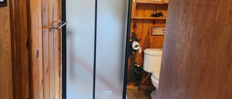 Un intérieur en bois avec une porte coulissante, un sol carrelé et un petit meuble sur lequel est apposée une enseigne.