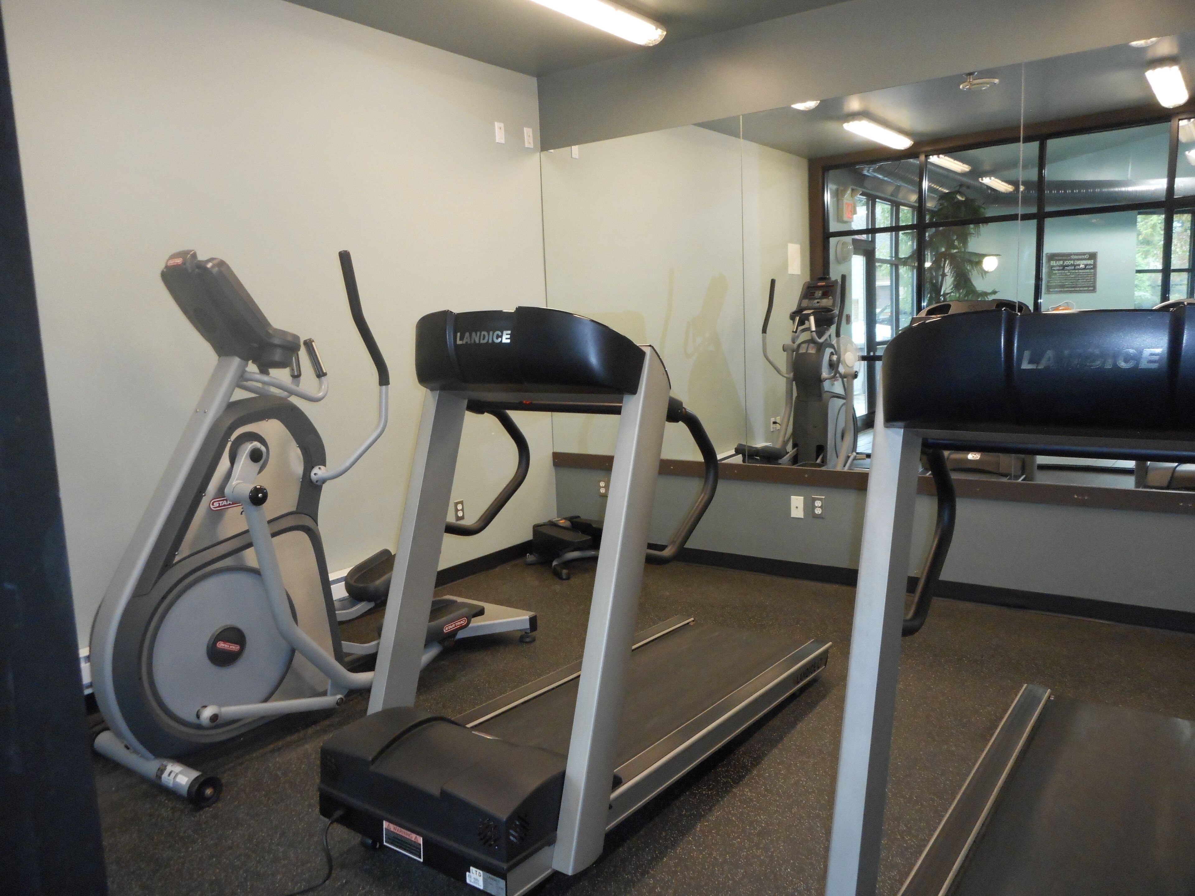 Une salle de sport équipée d’un tapis de course, d’un vélo d’appartement et d’un appareil d’entraînement elliptique.