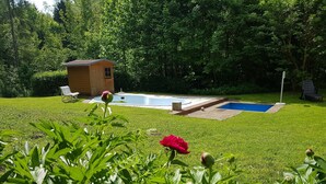 A backyard with a swimming pool, a wooden shed, and a lawn chair. - Verwöhn-Pension Wiesengrund (Bischofsgruen)