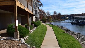 A riverside walkway with a building featuring balconies and a view of the water. -  Remodeled Ledges Lakefront 2BR Condo! No Steps. Walk-In Unit w/ WiFi. (Osage Beach)