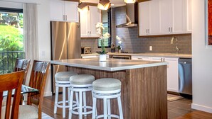 Een moderne keuken met een groot kookeiland, barstoelen en hanglampen.
