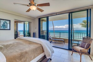 Relax in this serene space with a large bed, ceiling fan, and sliding glass door leading to a balcony overlooking the ocean.