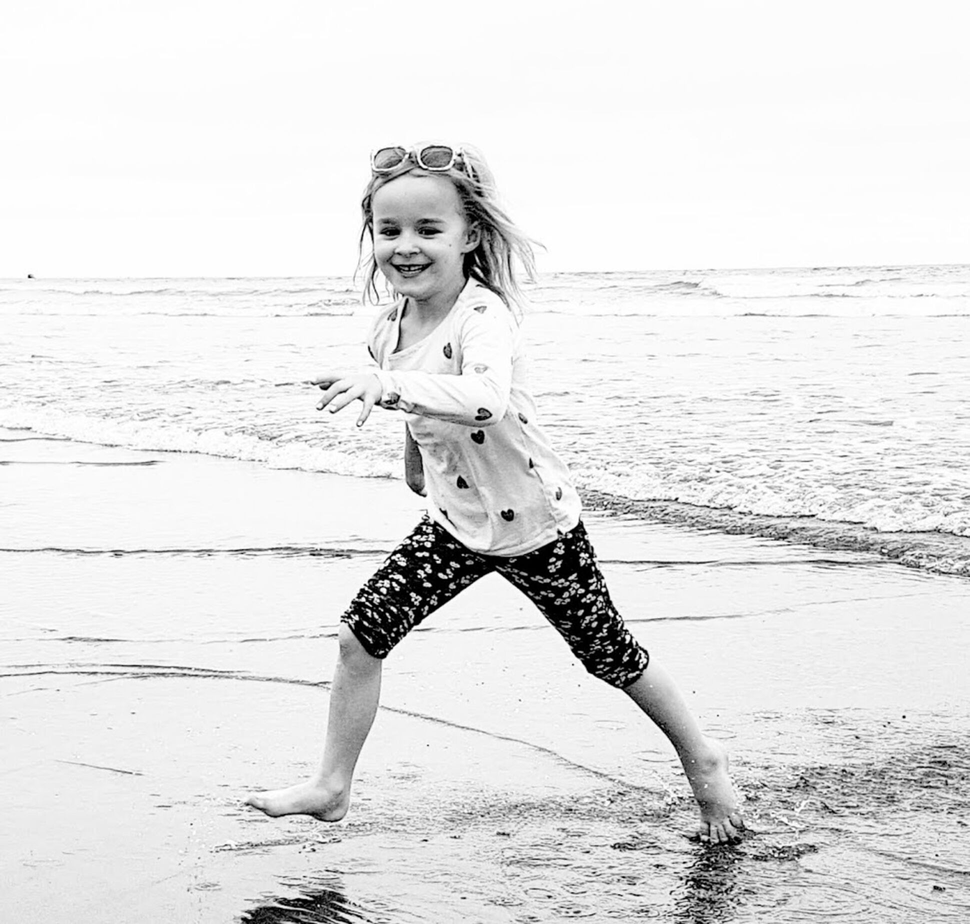 A child playing on a beach with waves in the background.