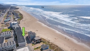 A coastal residential area with a beach, houses, and a road.