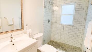 A bathroom with a white sink, toilet, and shower.