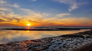 A sunset over a calm body of water with a clear sky. - Charming Cape Cod cottage on Depot Pond & bike trail with pond access (Eastham)