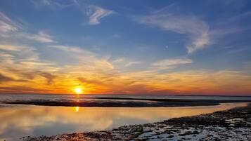 A sunset over a calm body of water with a clear sky.
