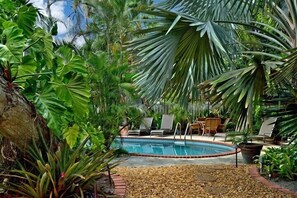 Relax by the serene pool surrounded by lush tropical plants and palm trees.