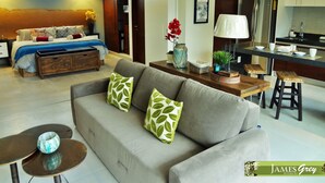 A modern living room with a sofa, coffee table, and a dining area with a kitchen in the background. - Amazing Tao loft overlooking the golf course. (Akumal)