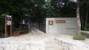A Wellness Center entrance with a sign, a staircase, and a surrounding natural environment. - Amazing Tao loft overlooking the golf course. (Akumal)