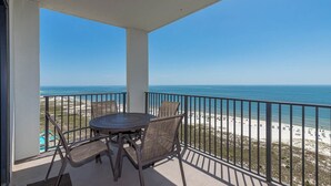 A balcony with a table and chairs, overlooking a beach with a clear view of the ocean. - 2 Bedroom Sleeps 8! Phoenix VI 61509 (Orange Beach)