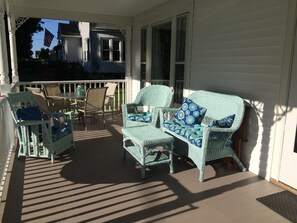Relax on the covered porch with wicker furniture and a small table, perfect for social gatherings.