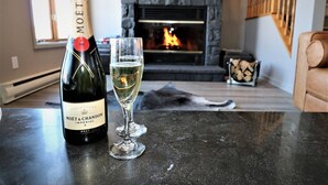 A bottle of Moët & Chandon Imperial champagne and a glass of champagne on a table in a room with a fireplace. - Tremblant Prestige - Clairiere 404 (Mont-Tremblant)