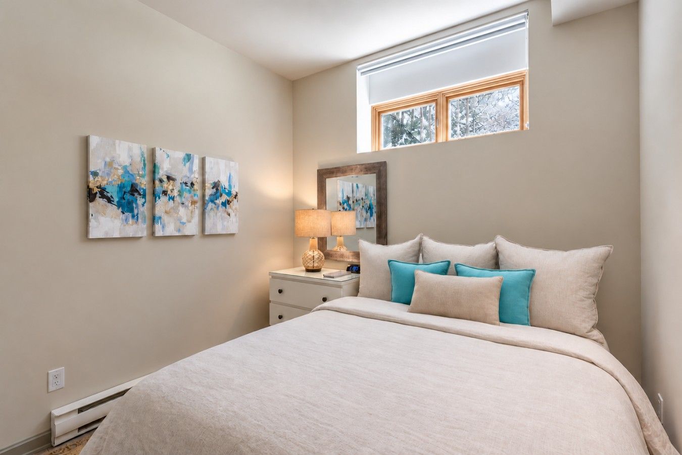 A bedroom with a bed, a nightstand, a lamp, and three wall-mounted paintings.
