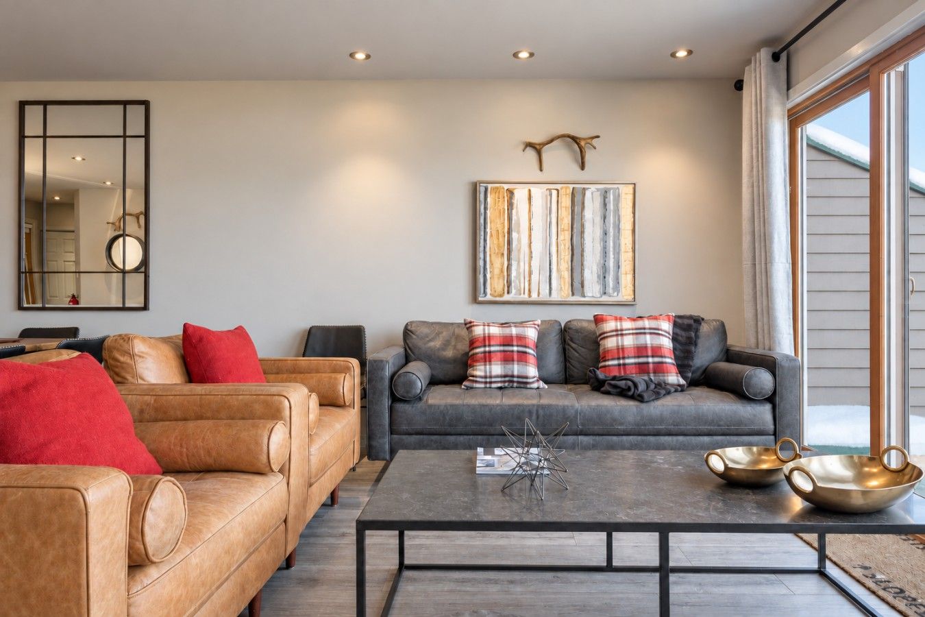 A modern living room with leather sofas, a coffee table, and a large window.