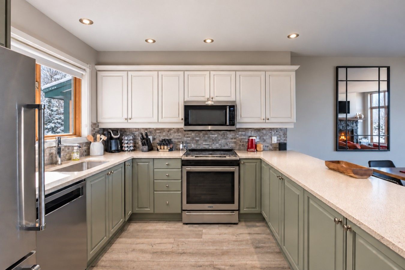 A modern kitchen with white cabinets, a stainless steel refrigerator, a microwave, and an oven.
