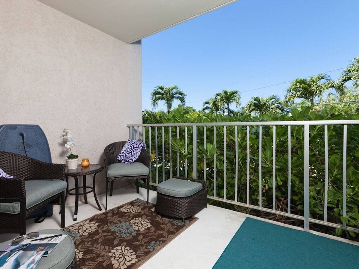 A balcony with wicker furniture, a small table, and a potted plant.