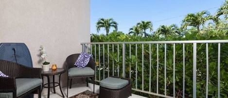 A balcony with wicker furniture, a small table, and a potted plant.