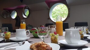 A breakfast setting with multiple dining tables, fruit bowls, and beverages. - Péniche Amboise Maison d'hôtes Toulouse (Toulouse)