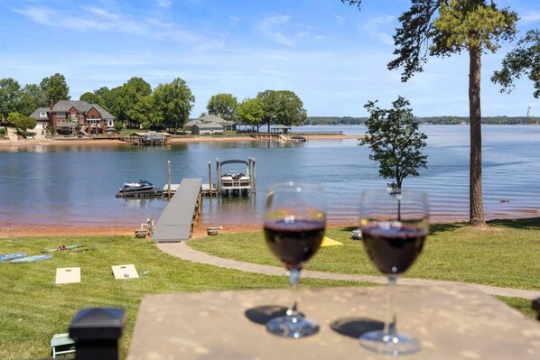 A lakeside view with a dock, boats, and a house in the background.