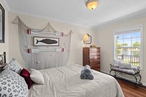 A bedroom with a bed, a dresser, a bench by the window, and a wall-mounted picture.