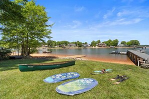A lakeside setting with a canoe, paddleboards, and a dock.