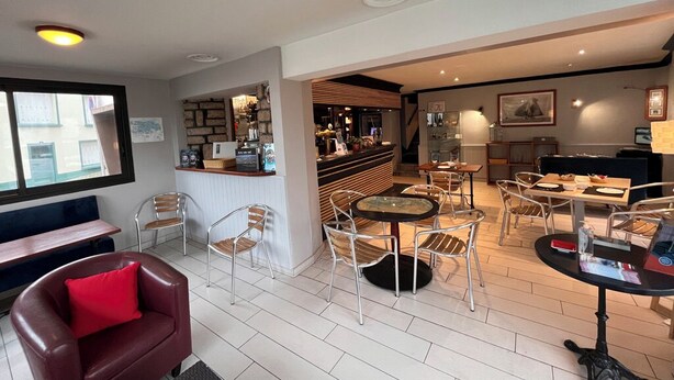 A modern hotel lobby with a bar area, seating arrangements, and a view of the street. - Hôtel des Iles (Theix-Noyalo)