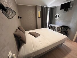 Une chambre à coucher avec un lit, un bureau, une chaise, une télévision et un miroir.