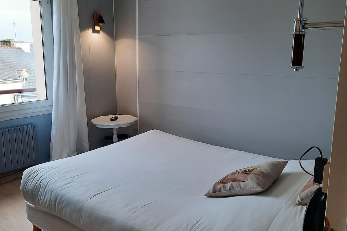 A bedroom with a bed, a bedside table, a lamp, and a phone.