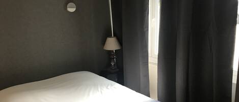 A bedroom with a bed, a lamp, and a window with curtains.