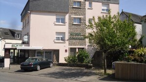 A hotel with a stone facade, a bar, and a parked car in front. - Hôtel des Iles (Theix-Noyalo)