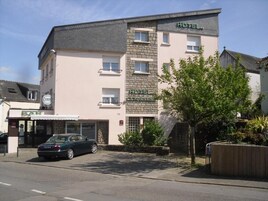 Un hôtel à la façade en pierre, avec un bar et une voiture garée devant.