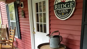 Un barril de madera en un porche con un letrero que dice "Ridge Cabin" y un cartel de bienvenida.