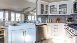 Una cocina moderna con armarios blancos, horno empotrado y estufa de acero inoxidable.