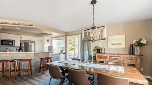 Una cocina moderna con una isla central, taburetes de bar y una mesa de comedor.