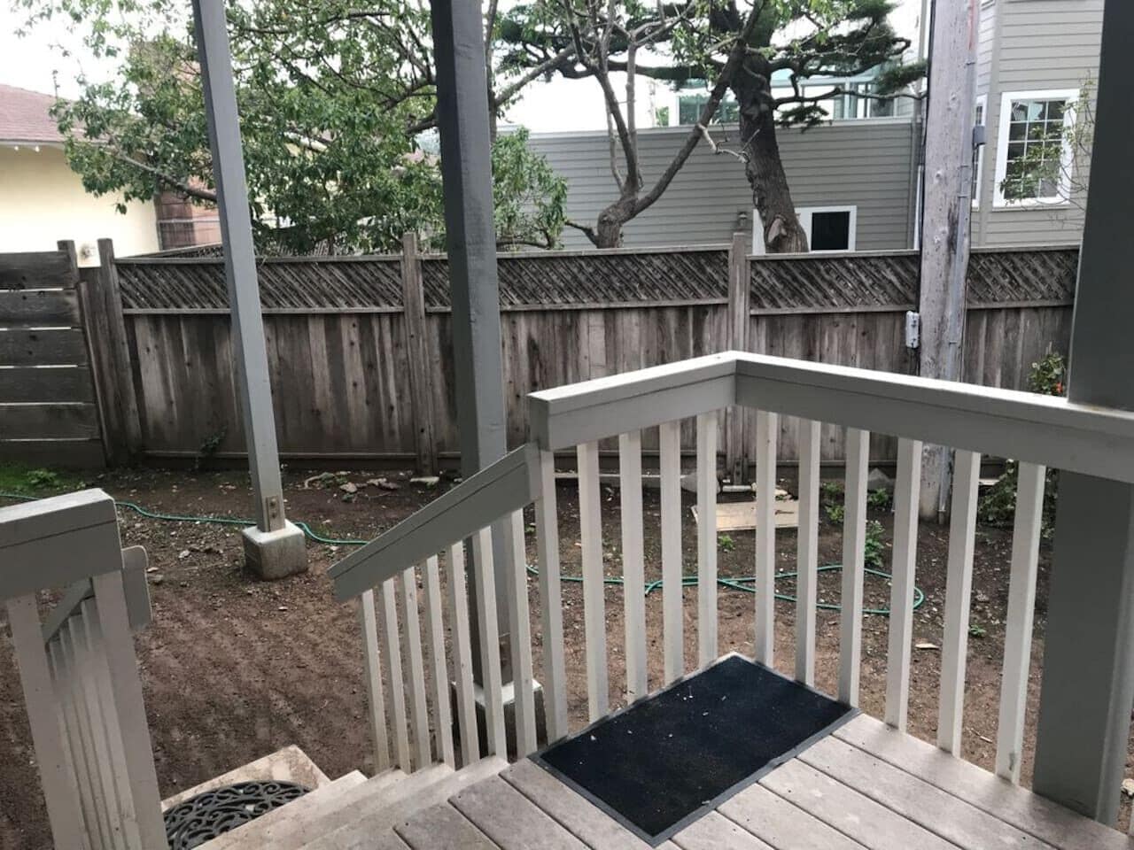 A wooden deck with a white railing and a black doormat.