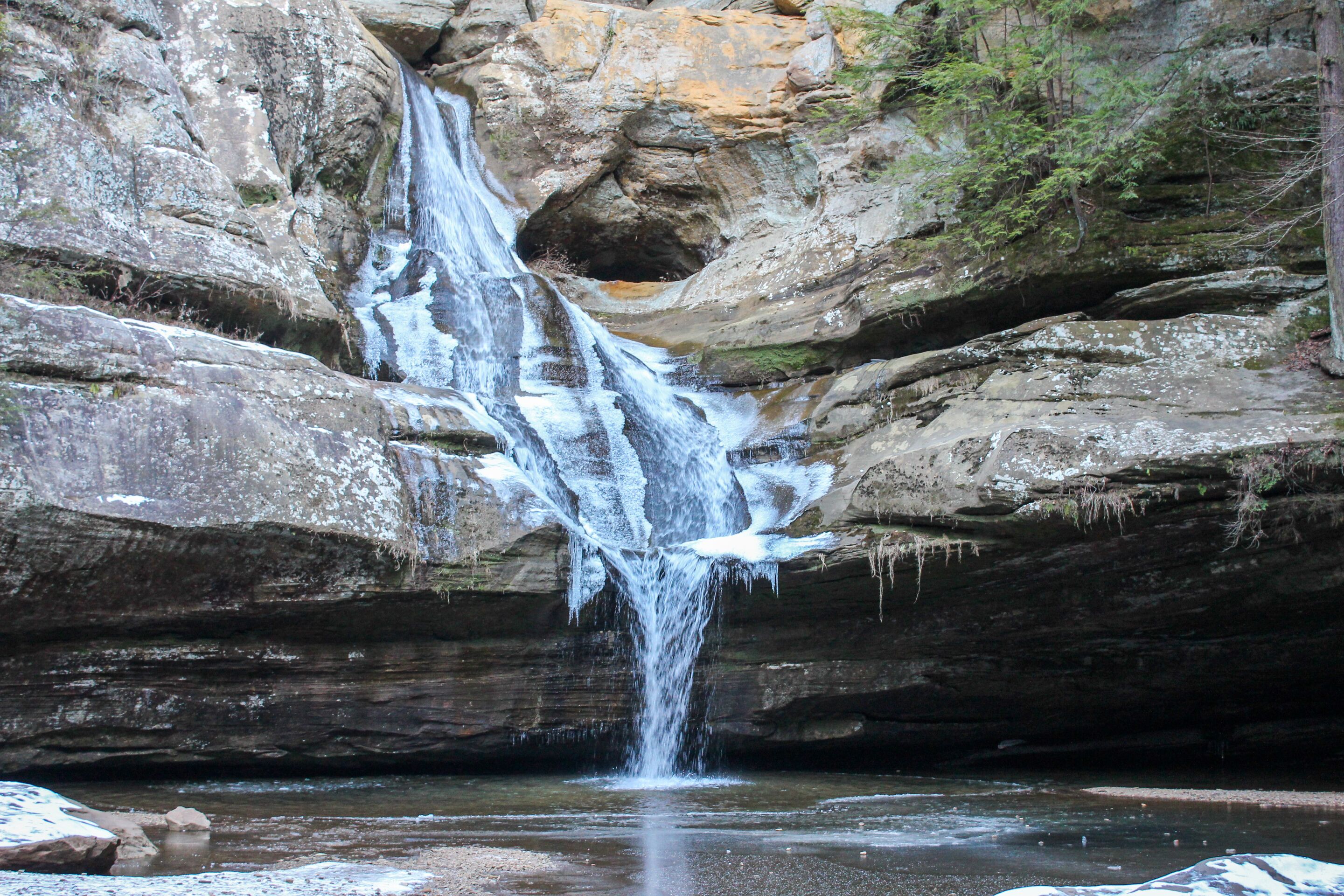 A waterfall cascading down a rocky cliff into a pool below.
