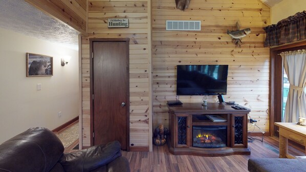A wooden-paneled room with a television, fireplace, and a door with a sign. - Pines Lodge at Sand Run Lake in WNF, Hocking Hills (Nelsonville)