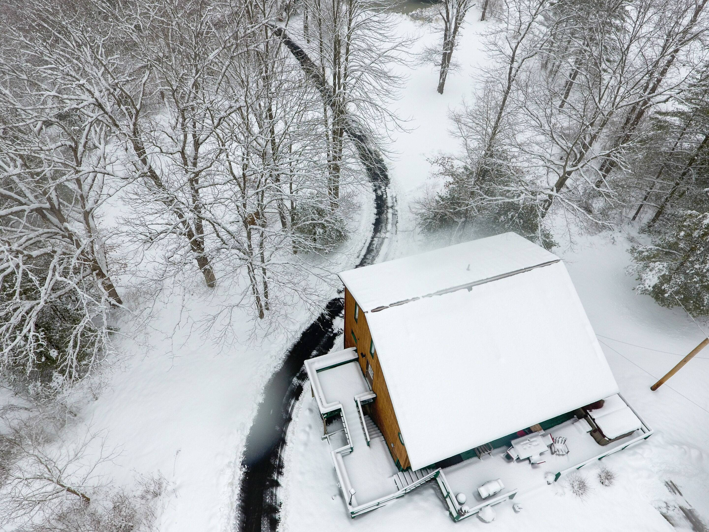 A snow-covered building with a flat roof, surrounded by trees.