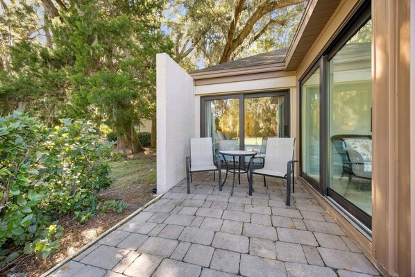 A patio with a table and chairs, surrounded by a garden and trees.