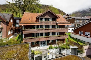 Un immeuble à plusieurs étages, doté de balcons, entouré de verdure et d’autres immeubles résidentiels.