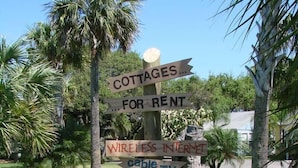 A wooden signpost with multiple directional signs advertising cottages for rent, wireless internet, cable TV, and full kitchens.