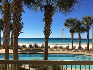 A pool area with lounge chairs and palm trees, overlooking a beach with a clear blue sky. - Ground Floor 1FL - Beachfront - Self Check-in/Out - Optional beach services (Panama City Beach)