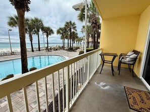 Un balcon avec une piscine, des chaises et une vue sur la plage et l’océan.